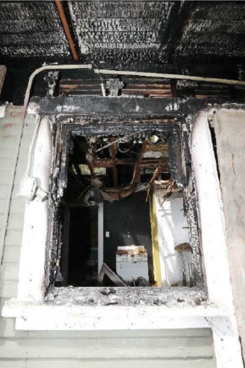 Photo of the charred open and exposed window later identified as the origination point of the March 18, 2022, arson. 